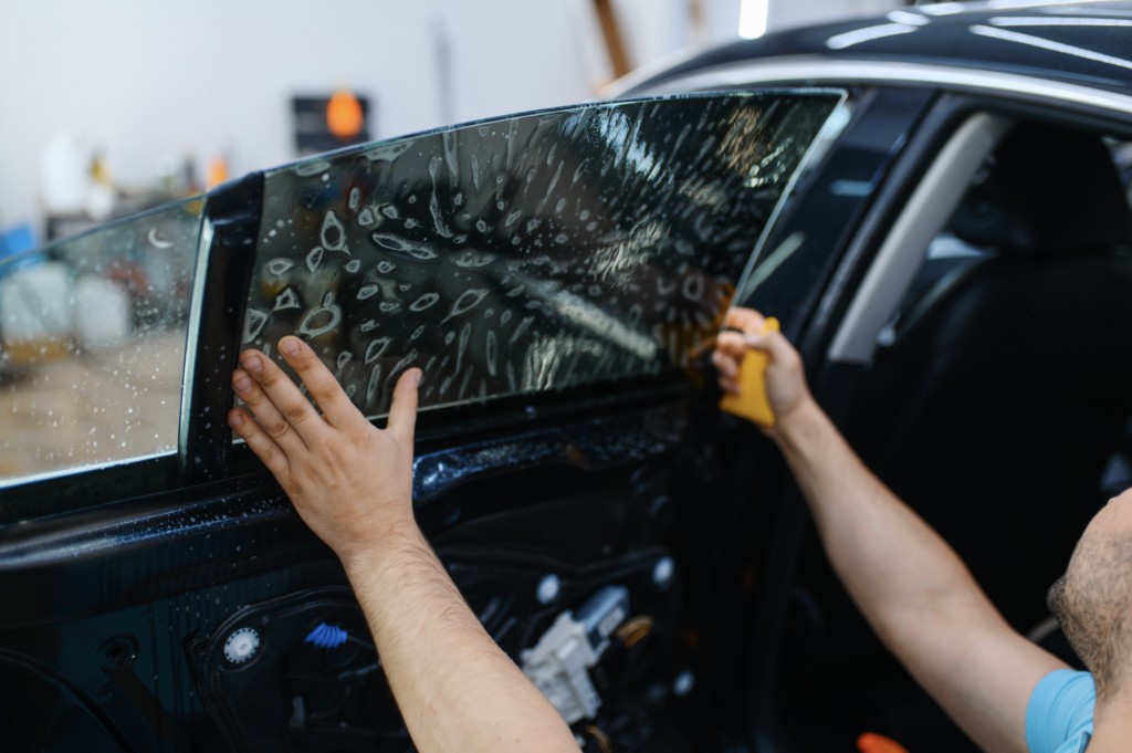 Installer fitting tint film on a car side window